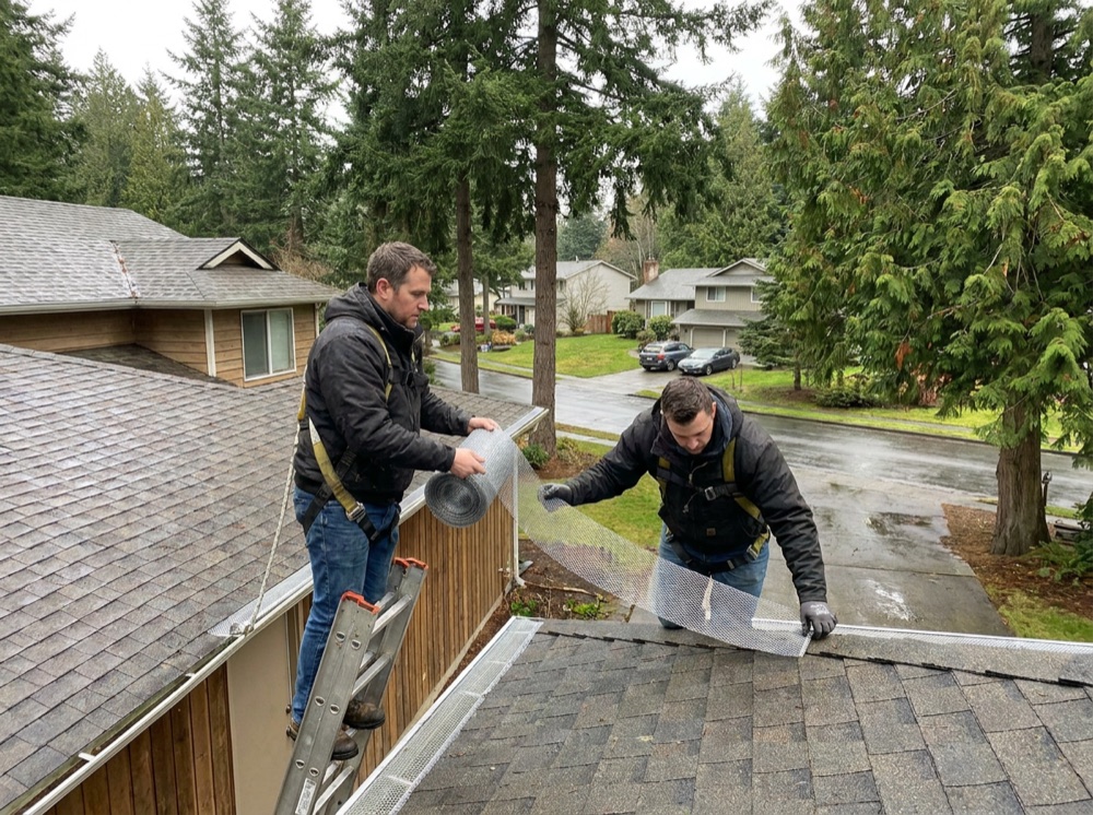 Gutter cleaning technician clearing roof gutters on a Tacoma home