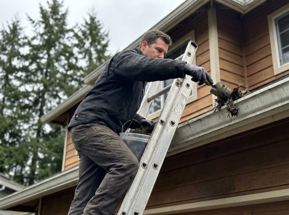 Gutter cleaning technician clearing roof gutters on a Seattle home